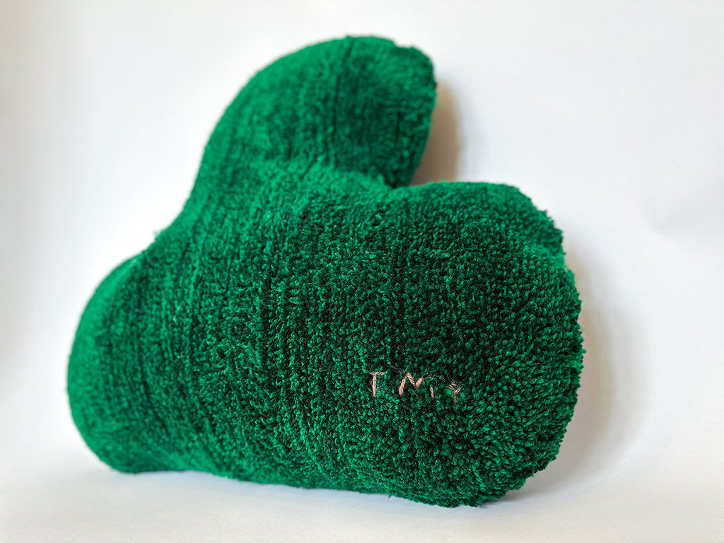 Side view of soft sculpture of a dark green leaf