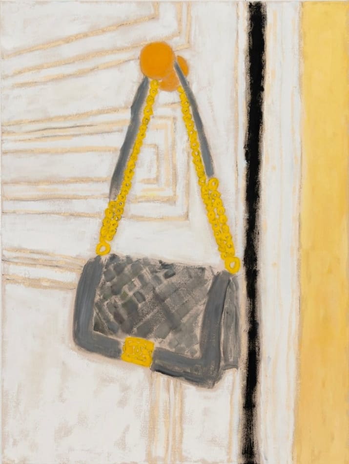 grey bag with gold accents hanging on doorknob of a white door