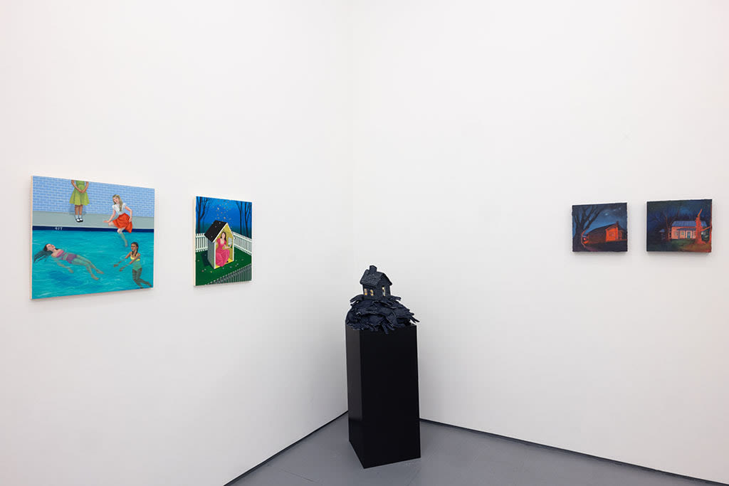 white gallery walls with paintings og various sizes and colors, and a black pedastal with a house sculpture