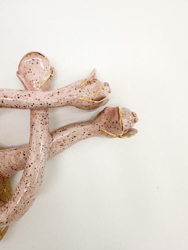 detail shot of sculpture by Jen Dwyer of light pink tentacle like objects emerging from brown mound with green leafs