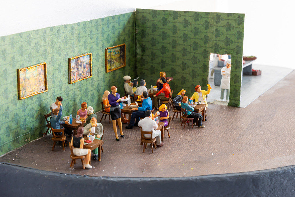 miniature diorama by Abigail Goldman of a restaurant with a human body being prepared in the kitchen s