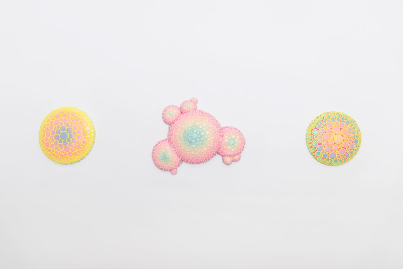 Installation shot of circular sculpture by Dan Lam with pink and purple circles and tiny bright yellow spikes