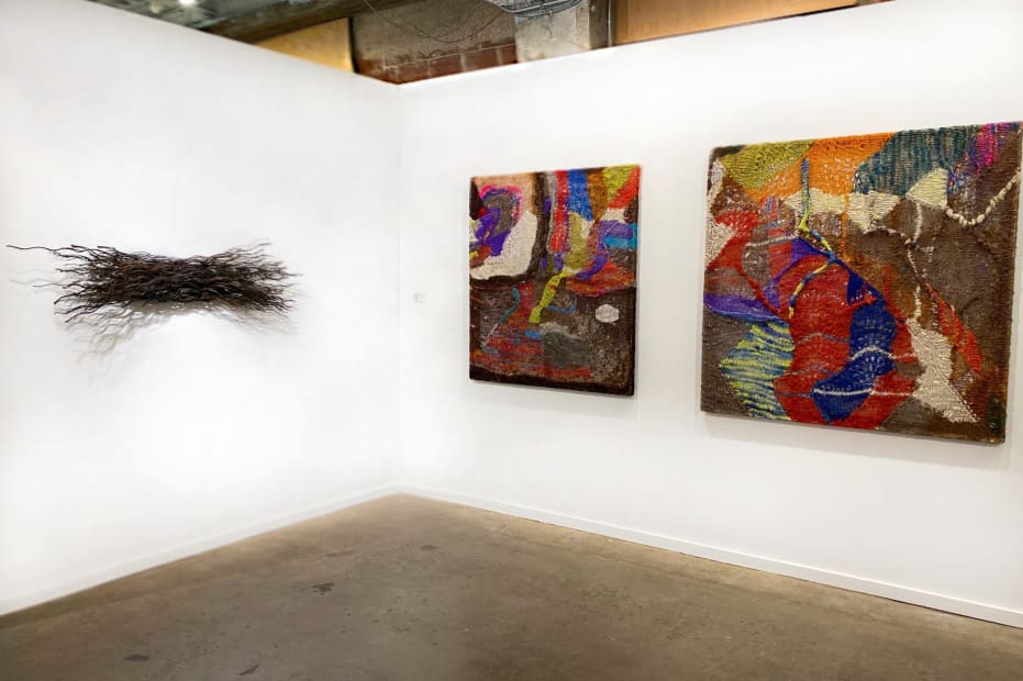 Installation view at the Dallas Art Fair with several colorful knitted works by Channing Hansen, red pots on plinths by Beverly Semmes, and a bundle of twisted wire rope on the wall by Maren Hassinger