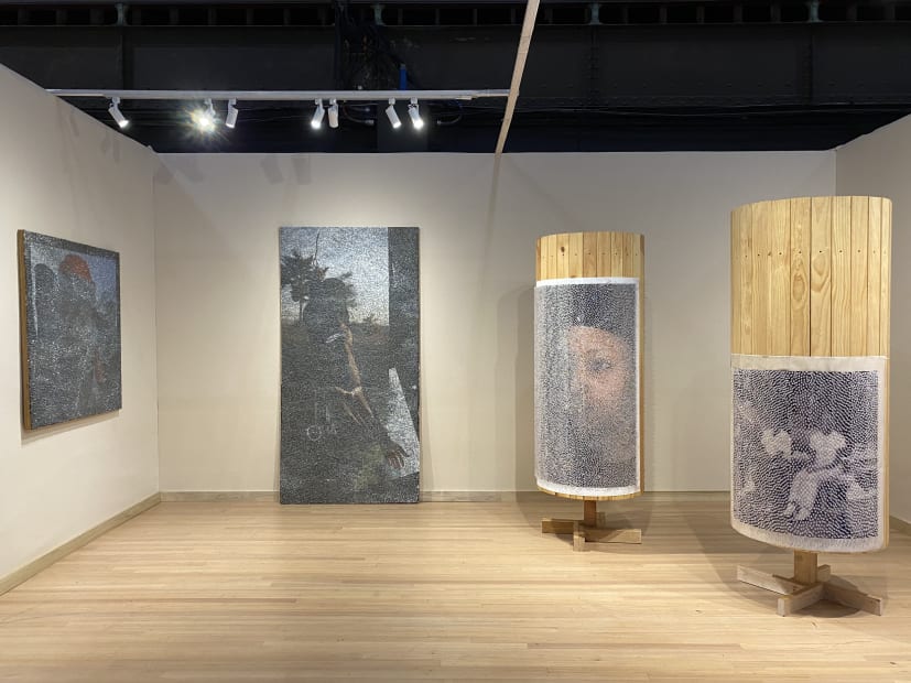 Installation of four Wilmer Wilson IV pieces, two panels covered in staples and two wooden cylinders with photographs and pushpins