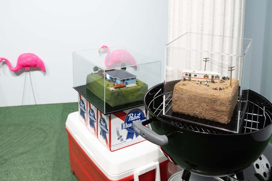 Abigail Goldman dieorama of RV murder scene in rocky / dirt landscape sitting on grill. Miniature of house sitting on beers and coolers
