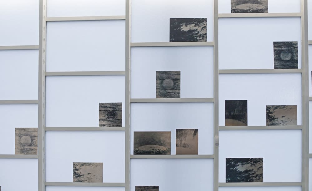Installation image of Lisa Oppenheim photographs on shelves