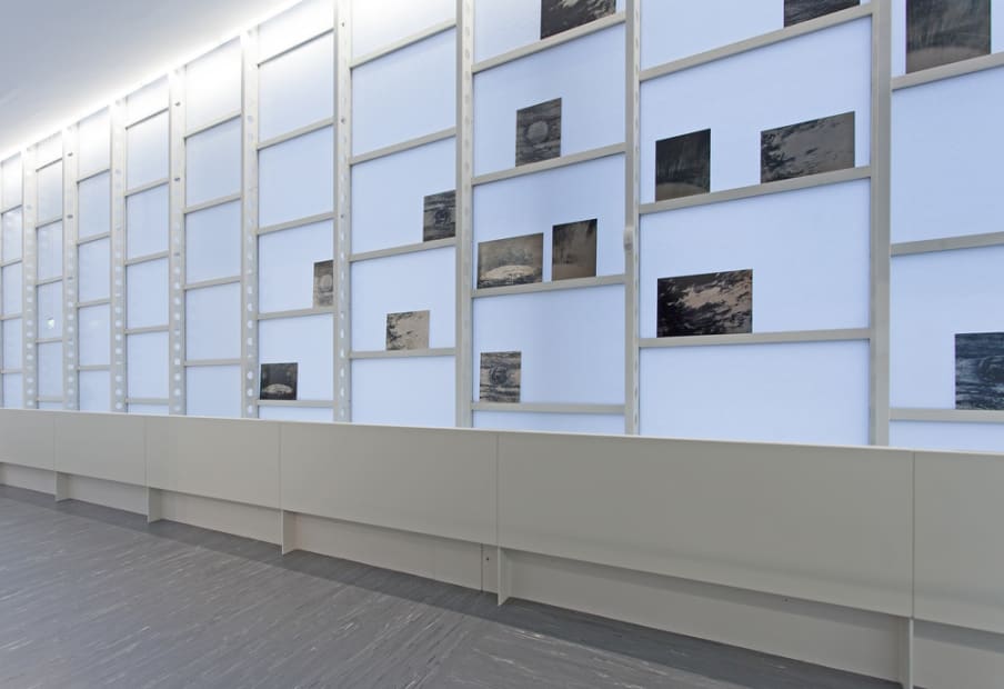 Installation image of Lisa Oppenheim photographs on shelves