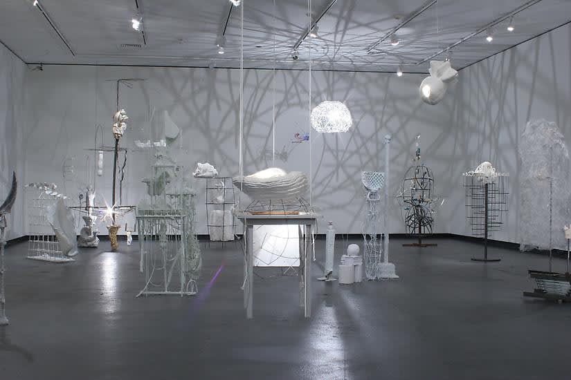 image of installation image of multiple Charles Long white sculptures, dim lighting and shadows
