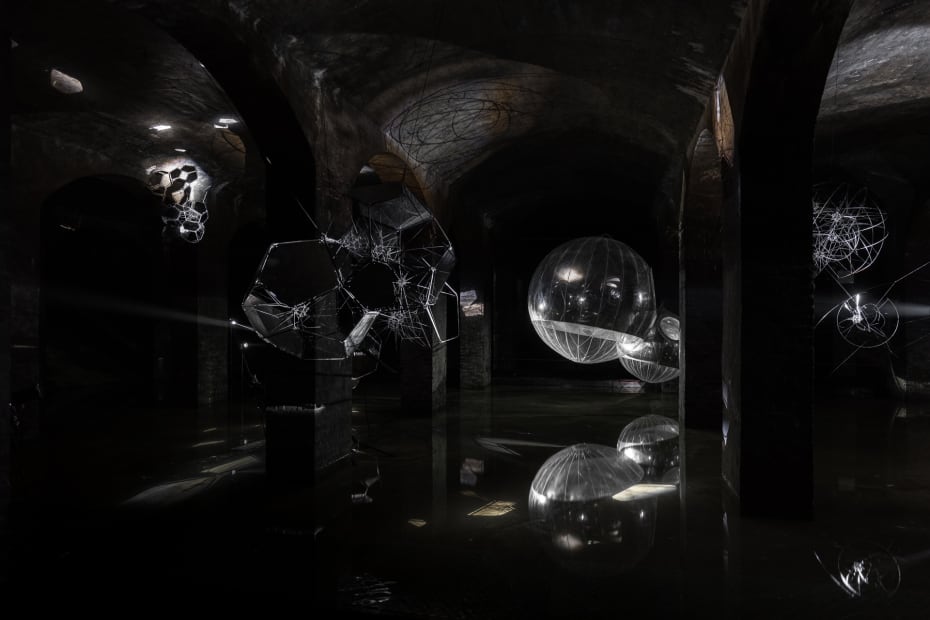 image of Saraceno sculptures hanging in dark room over water