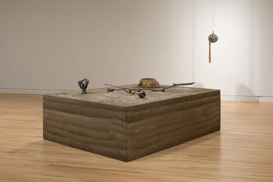 an earth colored sculpture within a gallery with white walls and wood floors