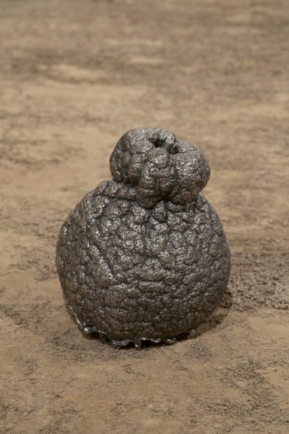 a bronze satsuma orange on an earthen pedestal