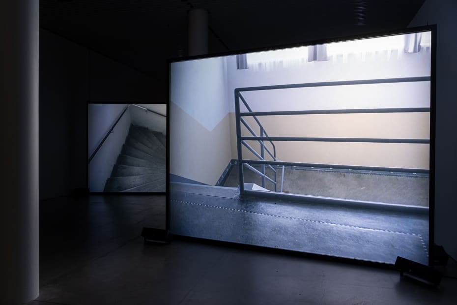 Susan Philipsz's film still image, two channel projection of concrete building facades in dark room