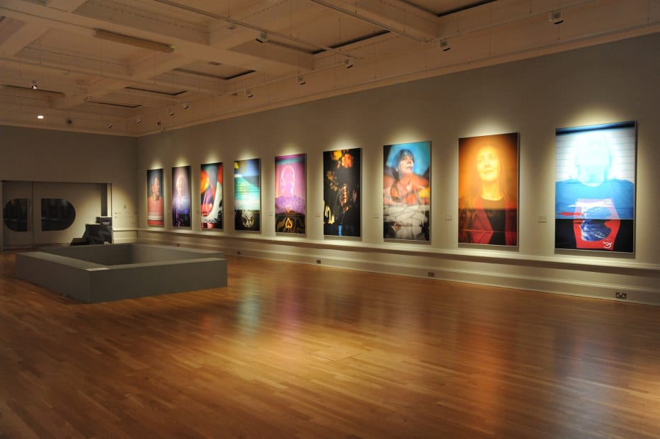 colorful portraits of women hung in a row on the right wall of a gallery