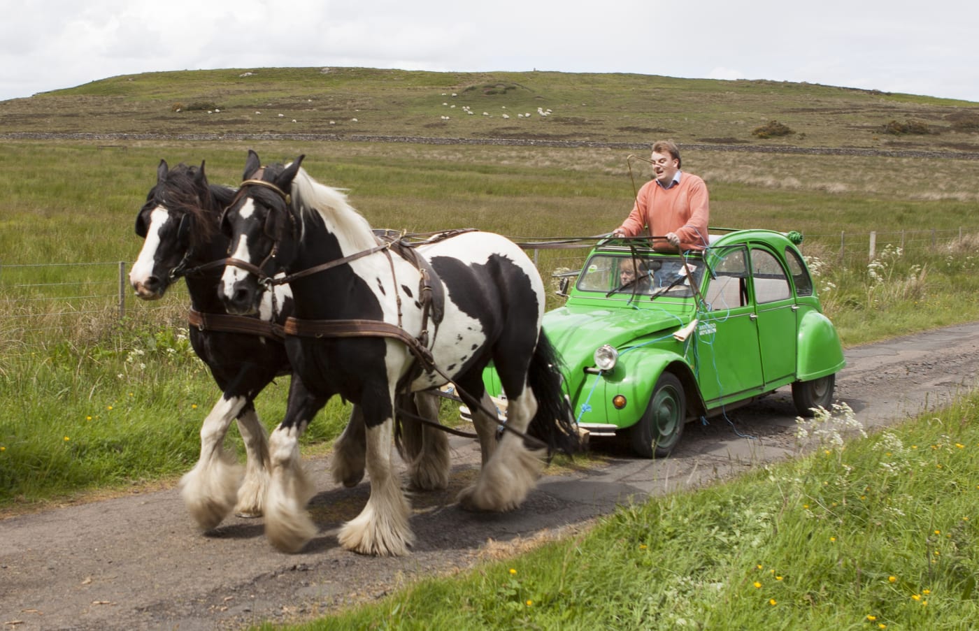 Deux Chevaux Performance piece, man riding a horses attached to a green car