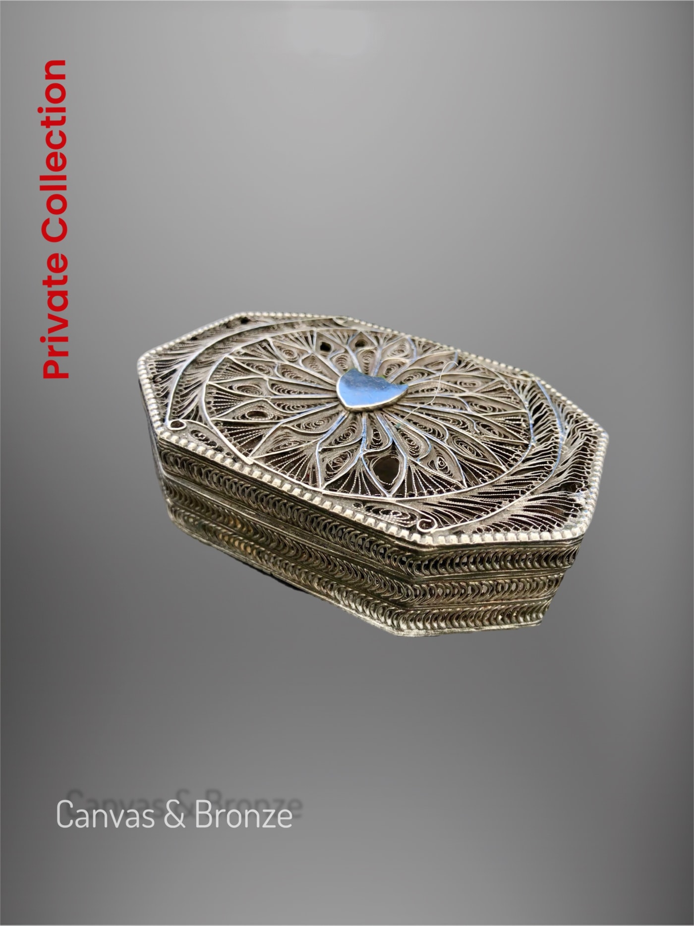Ornate silver filigree box with intricate detailing and a central blue accent, reflecting traditional craftsmanship.