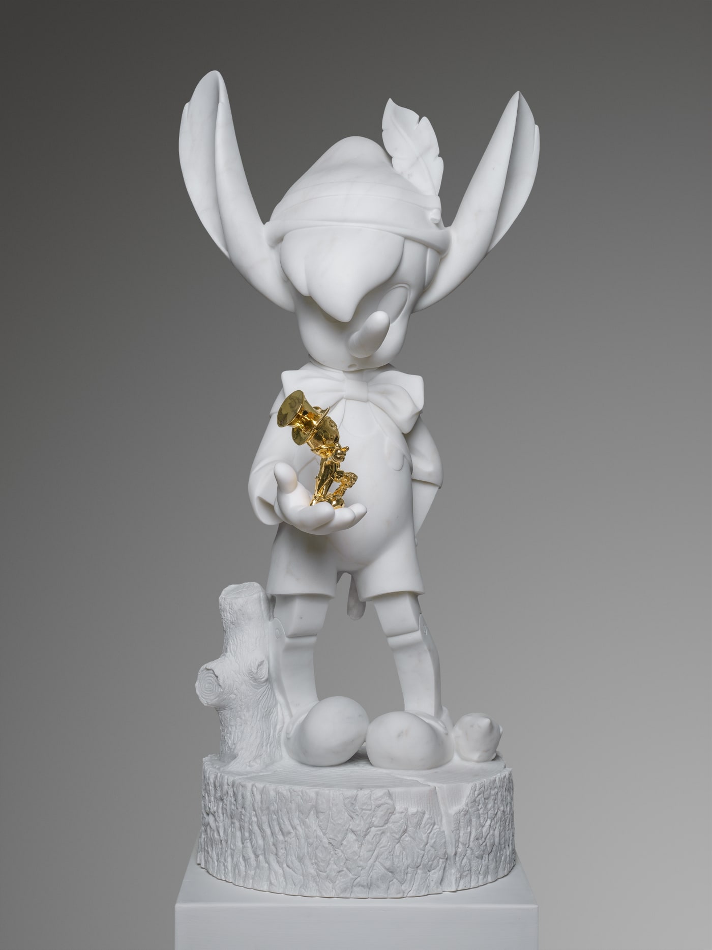 Marble sculpture featuring a pinocchio with a gold cricket, part of the 'Cartoon' series by artist Filippo Tincolini view from the front