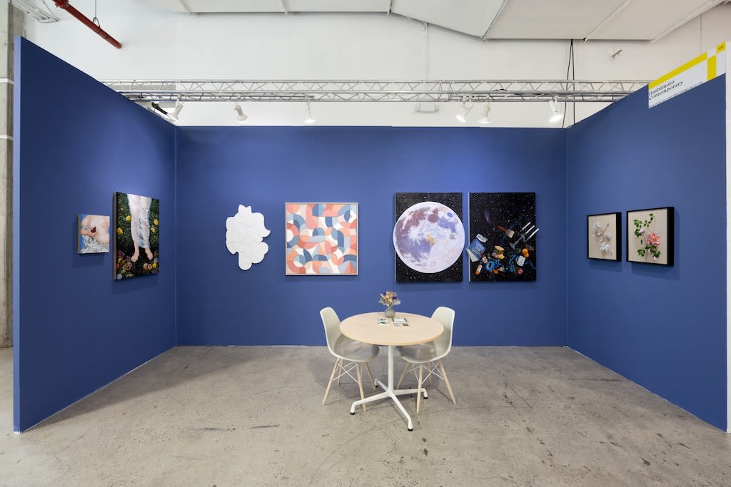 blue booth with various artworks hanging on walls. round table to the right