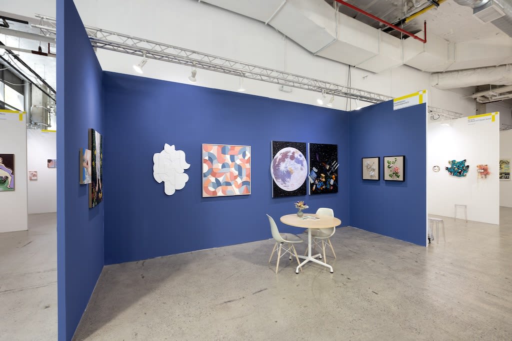 blue booth with various artworks hanging on walls. round table to the right