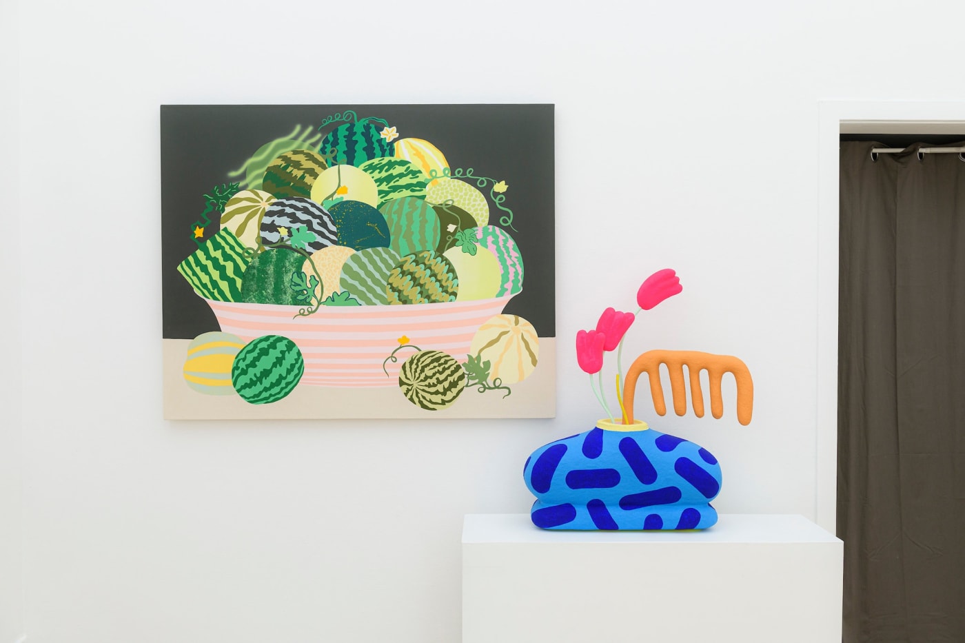 Potluck installation view - painting of watermelon on wall with colorful blue and pink vase in foreground