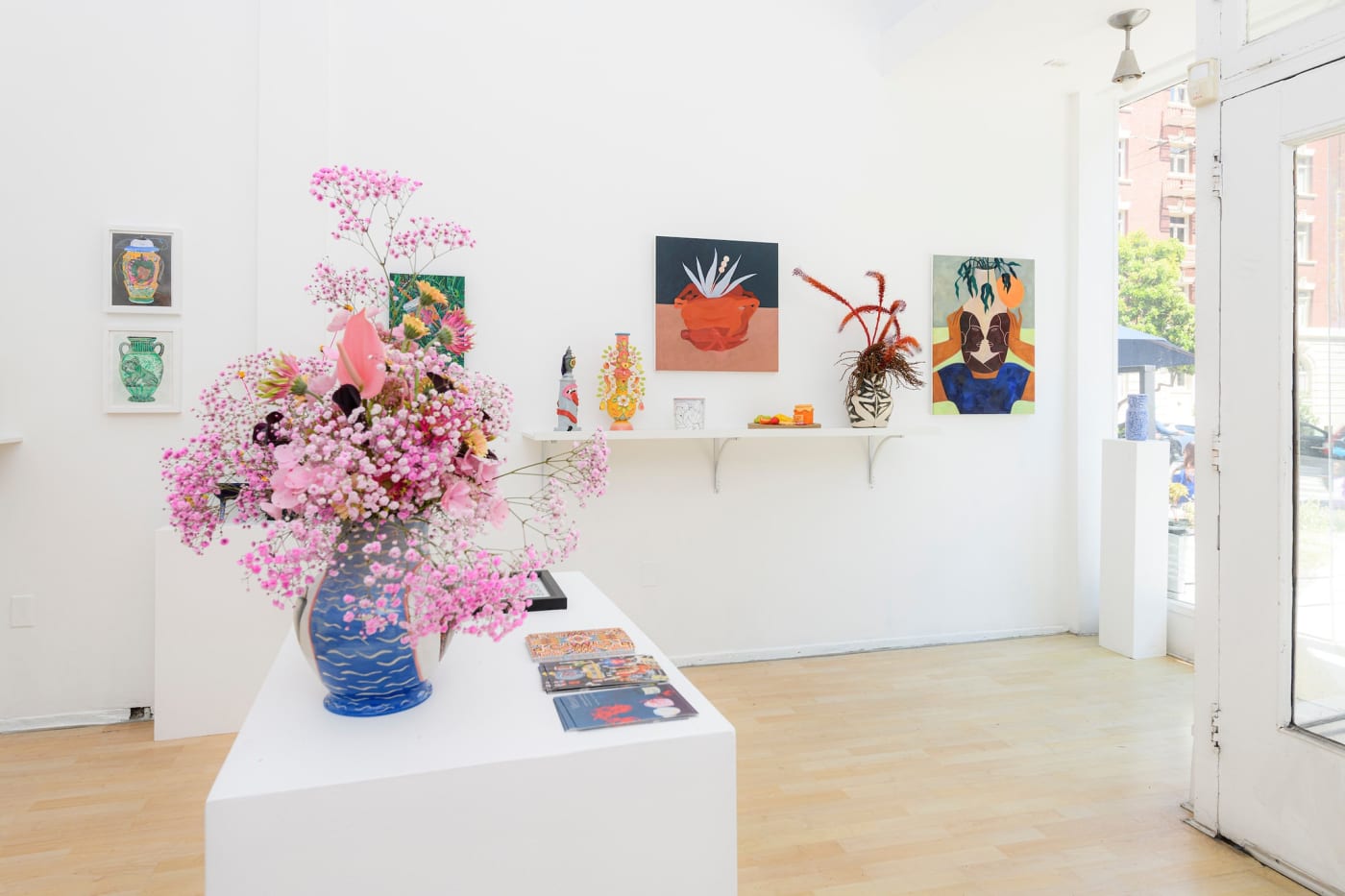 Vessel installation view - flower bouquet on table in foreground paintings of colorful forms in background