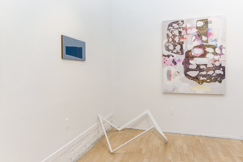 Exhibition installation view featuring abstracted sculptural work in foreground, paintings in background