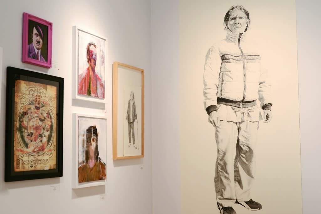 Art fair installation view featuring figurative work and framed paintings  