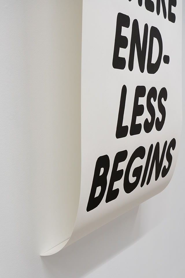 closeup image of black and white text artwork hung on a white wall
