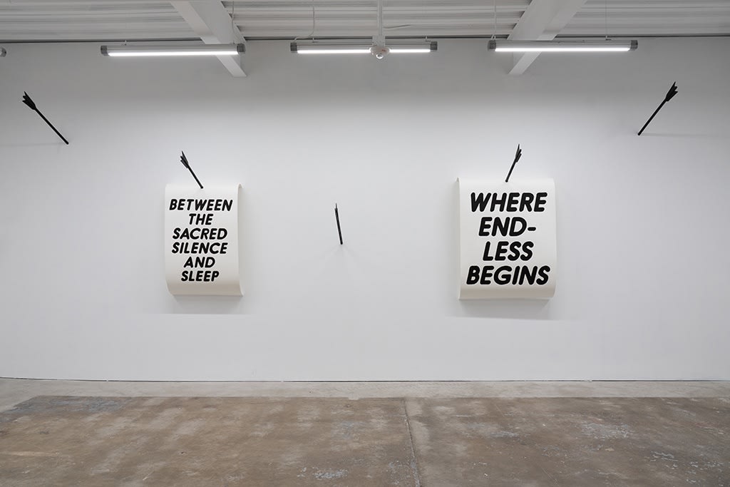 black and white text artwork hung on a white wall