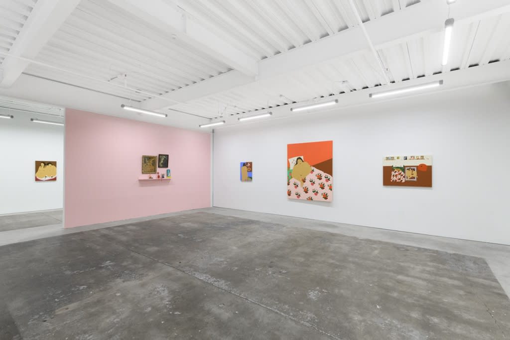 installation of Gina M. Contreras exhibition - pink wall to left with small sculptures and religious paintings, white wall along back and right side. Paintings of nude female figures with patterned floral bedding
