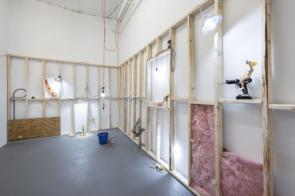 wooden scaffolding on white walls with dog human sculptures in various situations such as hanging from a wire and eating pizza around the room at the Stephen Morison Dog Show #4: House Broken exhibit