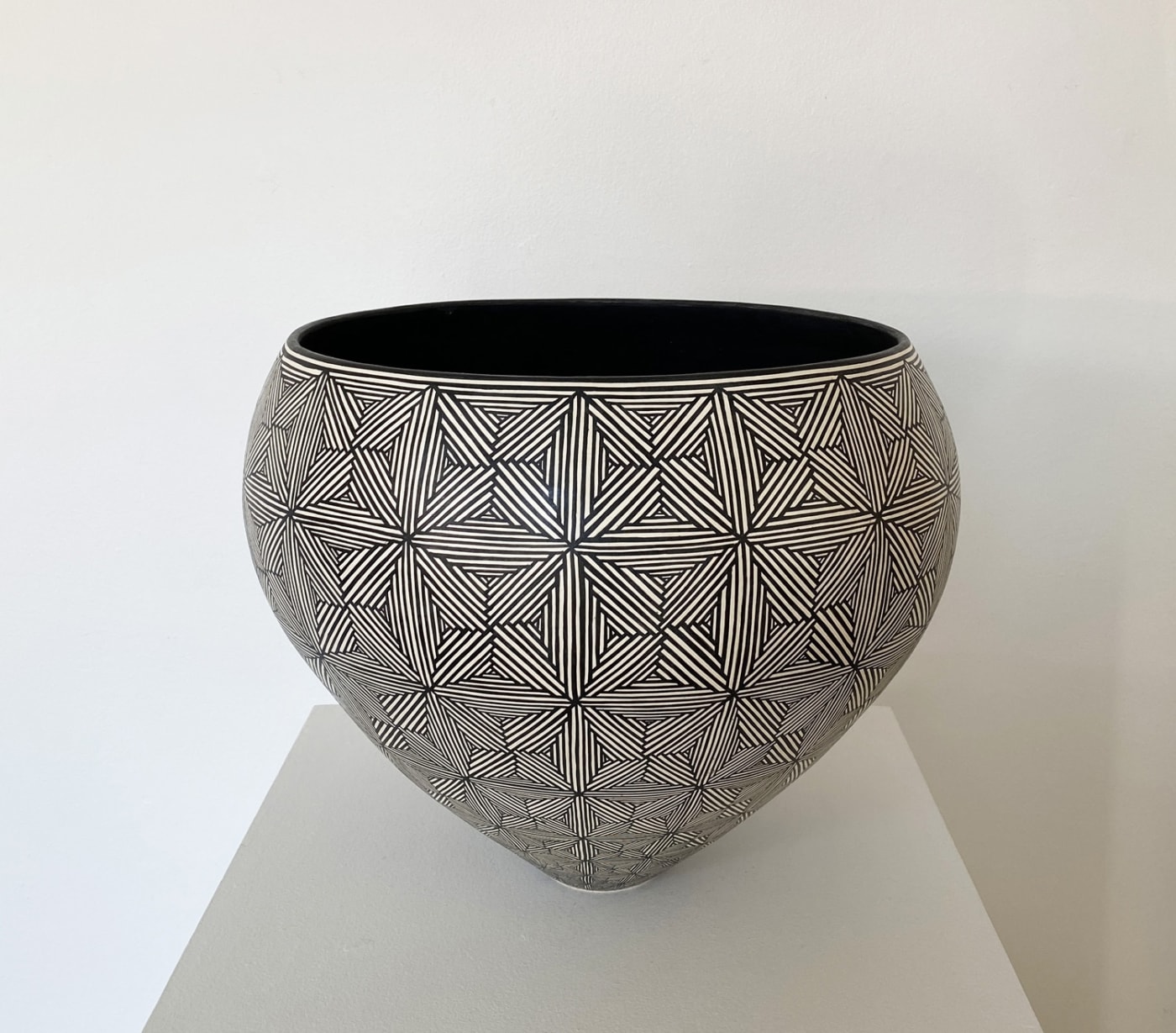Ant & Di Edmonds - Tydd Pottery wide, heart shaped ceramic black and white vessel with a complex star pattern.