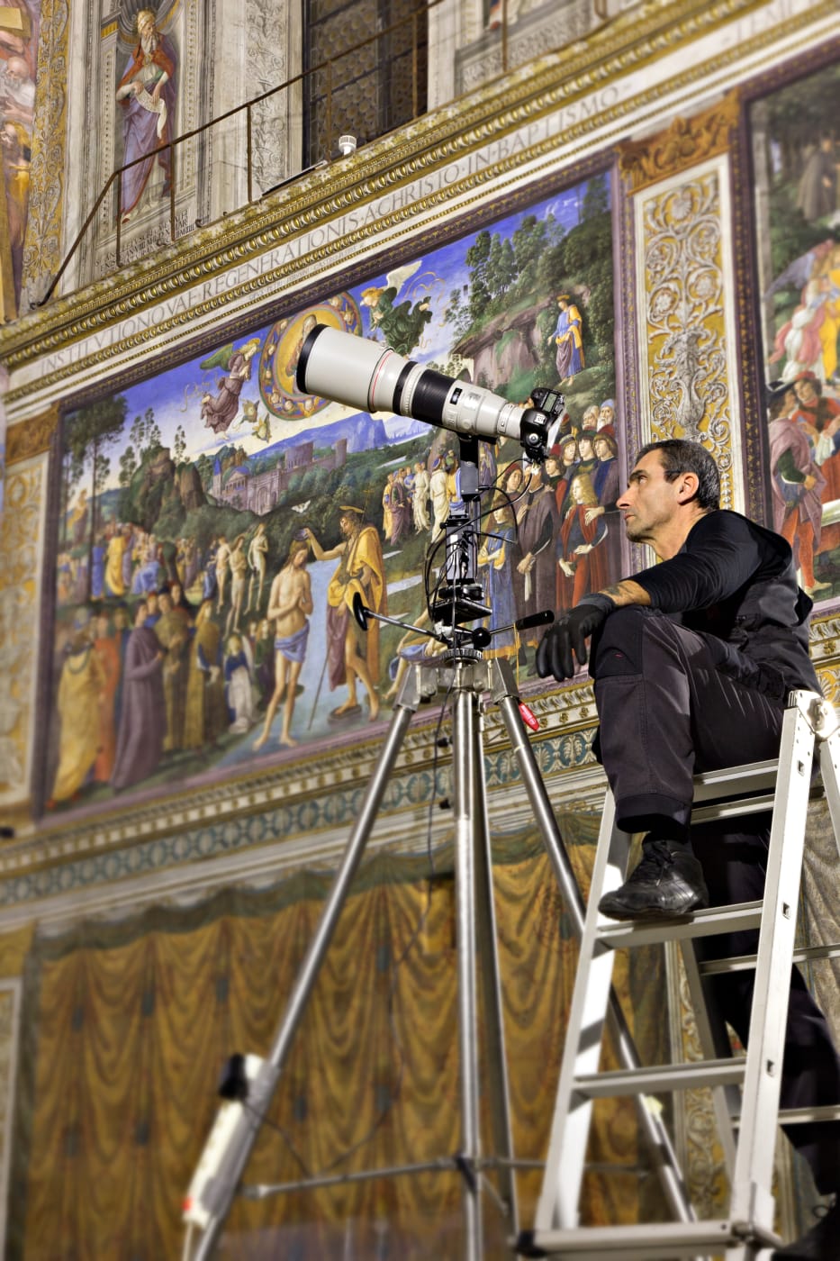 Photographer sitting on a ladder taking photographs of the Sistine Chapel for the new publication