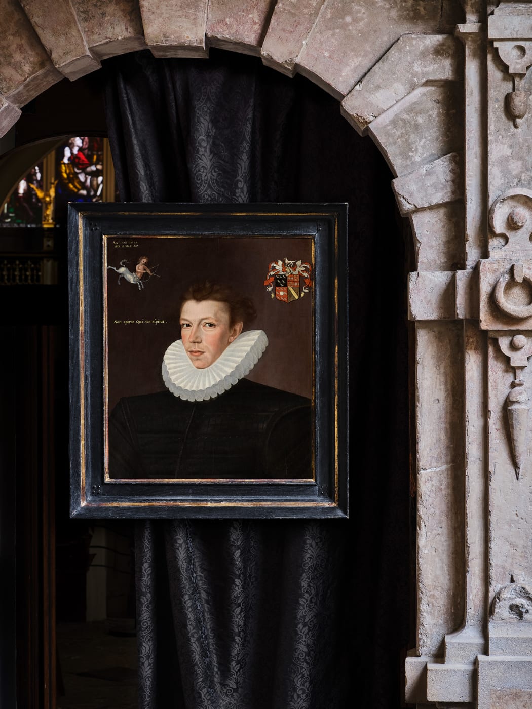 George Gower's Portrait of William Arundell hanging in a stone church interior