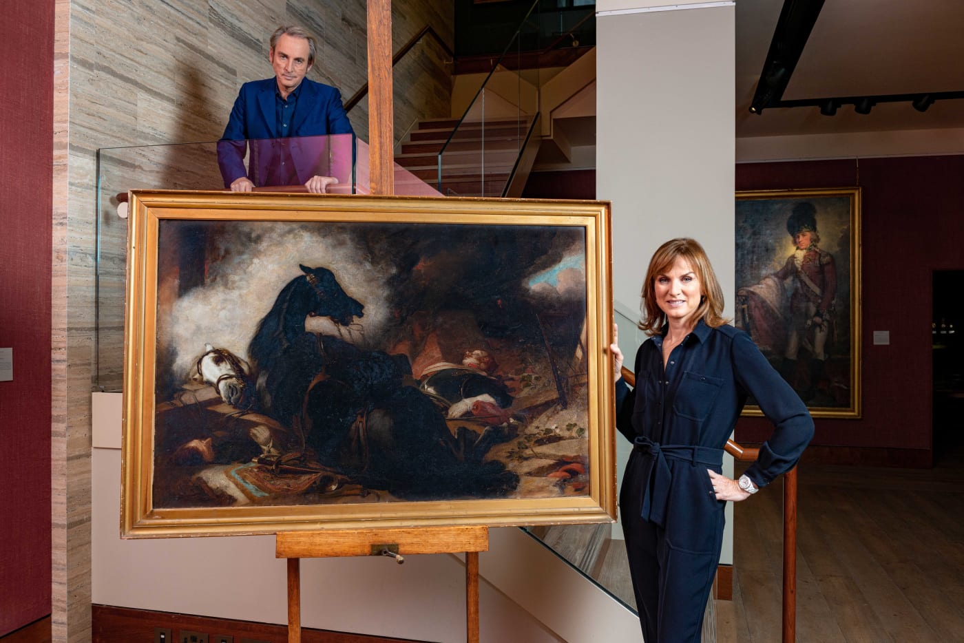 Philip Mould and Fiona Bruce photographed for Fake or Fortune infront of an artwork whiich could be by Edwin Landseer