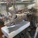 Bronzen beeld “Master of Speed V” van Lieven D’Haese, met een figuur in een gestileerd voertuig en een klein vogeltje op de voorkant.