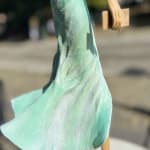 walking on a dream contemporary woman sculpture of Hedwige Leroux city girl in earphone listening to music and in green dress like a flower summer look bronze sculpture figurative sculpture at Art Yi gallery in Brussels