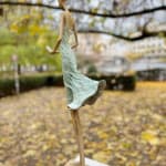 Waiting for a sign sculpture of Hedwige Leroux a girl sculpture contemporary sculpture contemporary woman sculpture bronze sculpture a young girl walking in her green dress and taping on the phone to wait for a message Art Yi gallery Brussels art gallery