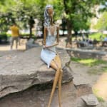 Stand by me vrouw sculptuur Hedwige Leroux hedendaagse kunst hedendaagse sculptuur interieurontwerp een sculptuur van een jong stadsmeisje dat in jeans ligt en naar muziek luistert een meisje dat zit en met haar koptelefoon naar muziek luistert Galerie Art Yi Brussels Art Gallery