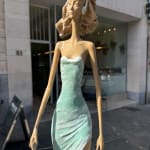 marchant sur un rêve sculpture contemporaine de femme de Hedwige Leroux fille de la ville dans un écouteur écoutant de la musique et en robe verte comme une fleur look d'été sculpture en bronze sculpture figurative à la galerie Art Yi à Bruxelles