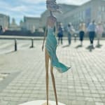 walking on a dream contemporary woman sculpture of Hedwige Leroux city girl in earphone listening to music and in green dress like a flower summer look bronze sculpture figurative sculpture at Art Yi gallery in Brussels