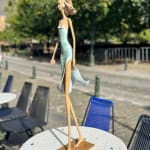 marchant sur un rêve sculpture contemporaine de femme de Hedwige Leroux fille de la ville dans un écouteur écoutant de la musique et en robe verte comme une fleur look d'été sculpture en bronze sculpture figurative à la galerie Art Yi à Bruxelles