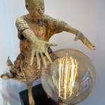 Visionary XL, sculpture lumineuse en bronze de Lieven d'Haese représentant un garçon ouvrant les bras pour allumer une ampoule, symbole d'imagination, de magie et de rêve. Sculpture d'art contemporain, design lumineux et design d'intérieur, exposée à la galerie Art Yi à Bruxelles.