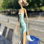 walking on a dream contemporary woman sculpture of Hedwige Leroux city girl in earphone listening to music and in green dress like a flower summer look bronze sculpture figurative sculpture at Art Yi gallery in Brussels