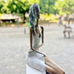 Stand by me sculpture de femme contemporaine Hedwige Leroux art contemporain sculpture contemporaine design d'intérieur une sculpture d'une jeune citadine allongée en jean et écoutant de la musique une fille assise écoutant de la musique avec ses écouteurs Galerie Art Yi Galerie d'art de Bruxelles