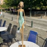 walking on a dream contemporary woman sculpture of Hedwige Leroux city girl in earphone listening to music and in green dress like a flower summer look bronze sculpture figurative sculpture at Art Yi gallery in Brussels