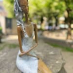 Stand by me sculpture de femme contemporaine Hedwige Leroux art contemporain sculpture contemporaine design d'intérieur une sculpture d'une jeune citadine allongée en jean et écoutant de la musique une fille assise écoutant de la musique avec ses écouteurs Galerie Art Yi Galerie d'art de Bruxelles