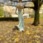 Waiting for a sign sculpture of Hedwige Leroux a girl sculpture contemporary sculpture contemporary woman sculpture bronze sculpture a young girl walking in her green dress and taping on the phone to wait for a message Art Yi gallery Brussels art gallery