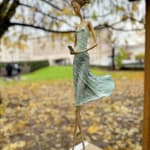 Waiting for a sign sculpture of Hedwige Leroux a girl sculpture contemporary sculpture contemporary woman sculpture bronze sculpture a young girl walking in her green dress and taping on the phone to wait for a message Art Yi gallery Brussels art gallery