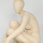 Seated white ceramic figure is looking over her left shoulder with arms draped around her knees which are tucked together.