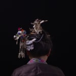 A video still from the section "Dressing" of Chen Qiulin's work "Another Day" where shows a village woman with beautiful hairpins turning her back on us.